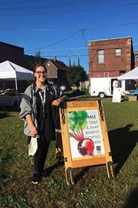 A person standing next to a sign
                                            
                                            Description automatically generated with medium confidence