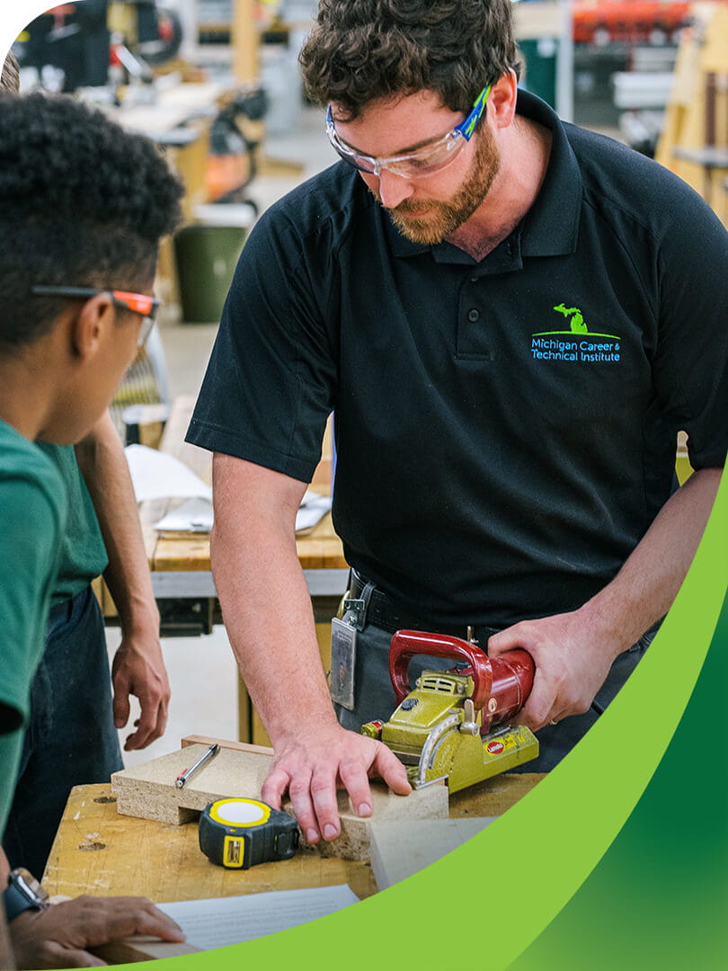 MCTI Cabinetmaking/Millwork instructor demonstrating to students how to properly use a plate joiner in a woodshop.
