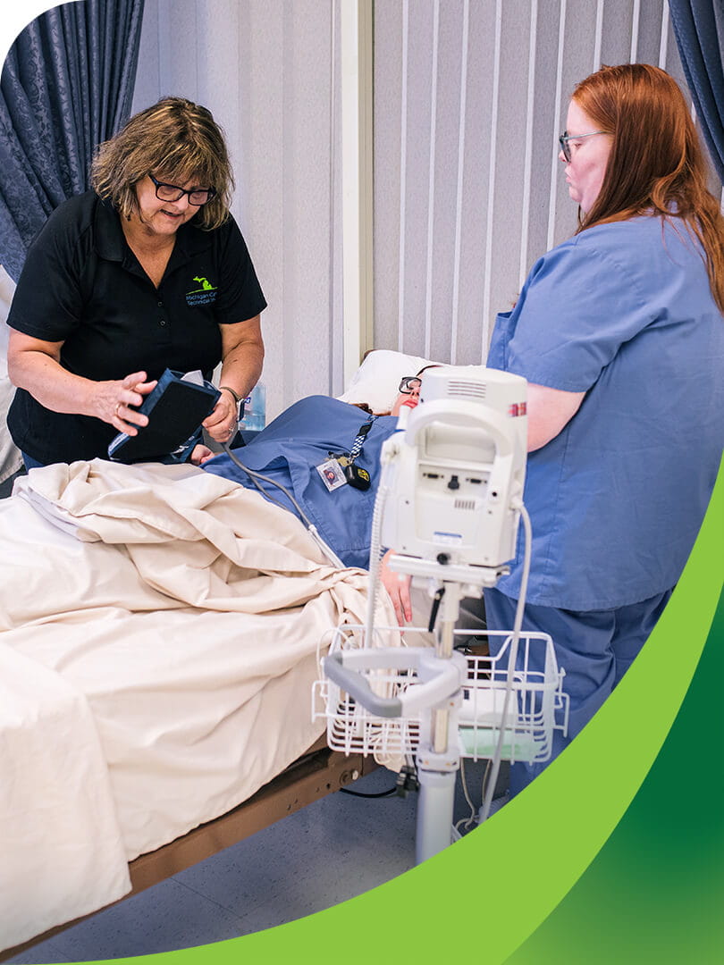 MCTI instructor in the CNA program demonstrates to two students how to take a patient's blood pressure.