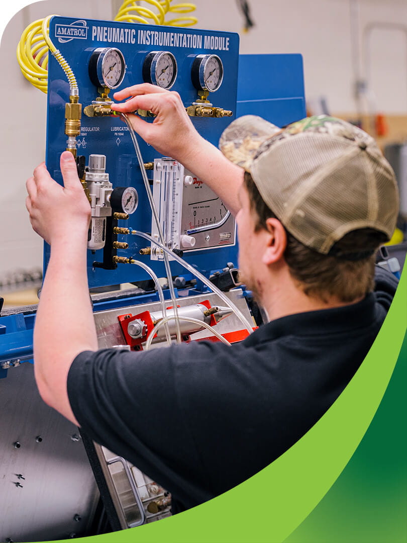 MCTI Industrial Electronics student operating an Amatrol pneumatic instrumentation module equipped with pressure gauges, regulators, valves, and actuators.
