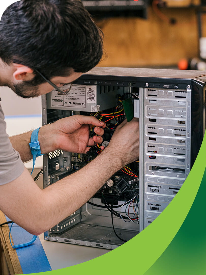 MCTI Information Technology student organizing cables and servicing internal components within an open tower desktop computer.