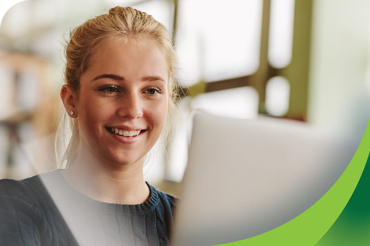 Young student smiling while using a laptop computer.