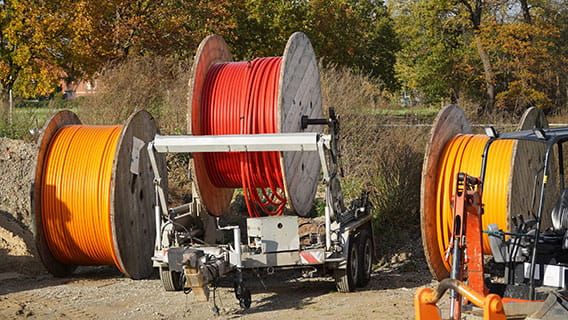 three wheels of fiber optic cable for broadband sitting outside with trees in the background
