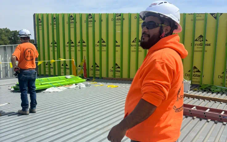 Two Sobie Company employees wearing Type II safety helmets work at a construction site.