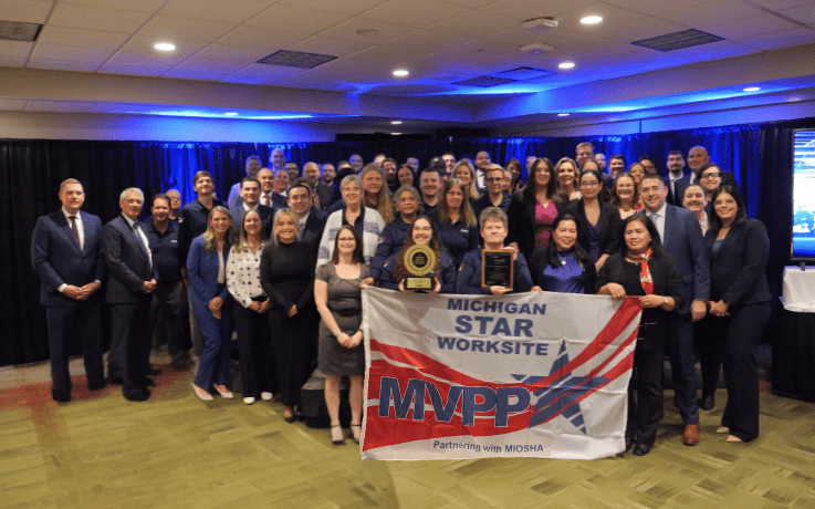 MIOSHA staff and Cintas employees pose with the Michigan MVPP Star Worksite flag and award plaque during the MVPP Star recognition event in Midland.