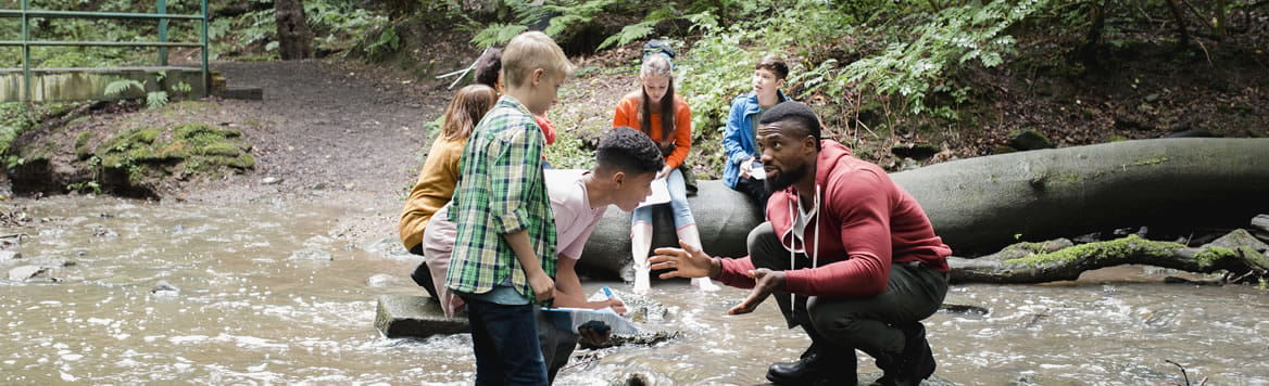teacher with young students making observations at a river