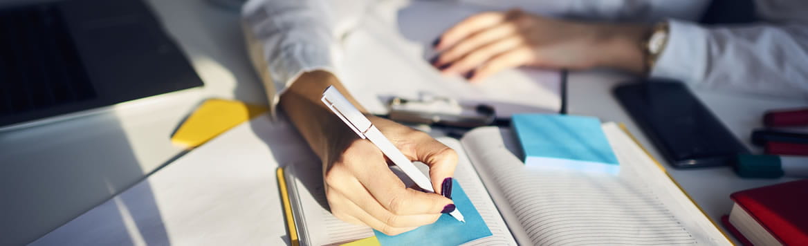 hands for a person at a desk writing on a sticky notepad