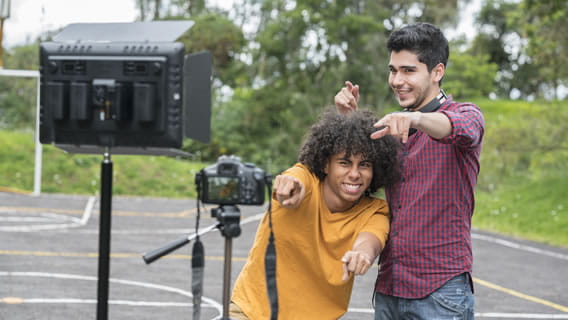 two teens outside in front of mounted camera making a video of themselves