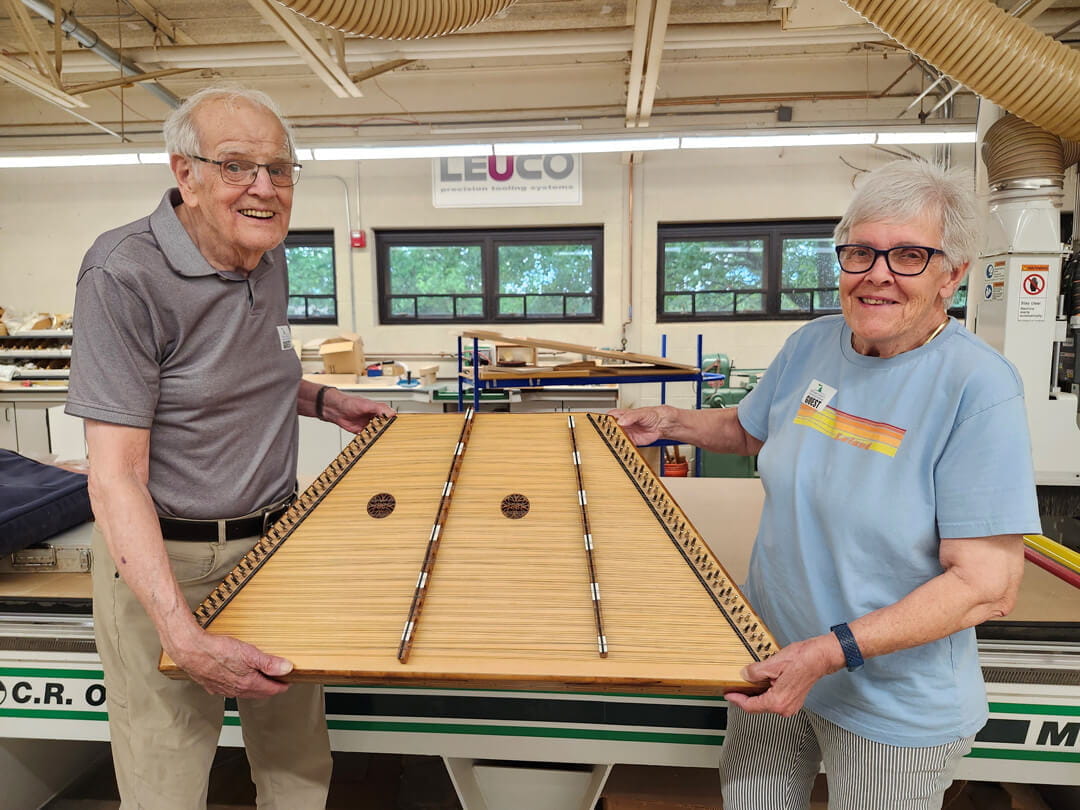 MCTI 1963 alumnus Garrett Mulder and his wife, Jean, holding a musical instrument hand-crafted by Mr. Mulder.