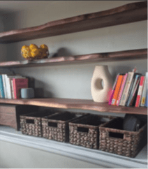 Three wooden shelves attached to the wall with various items on them.