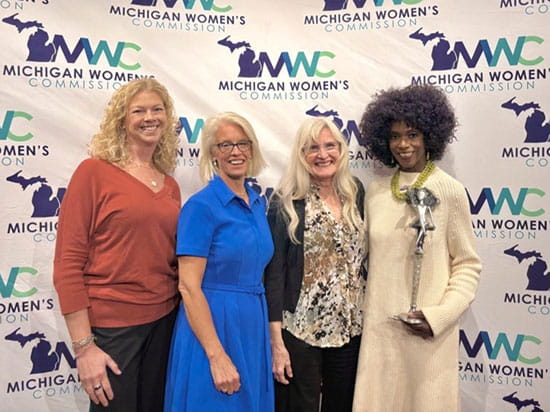 Four movie screening panelists stand in front of Michigan Woman's Commission backdrop