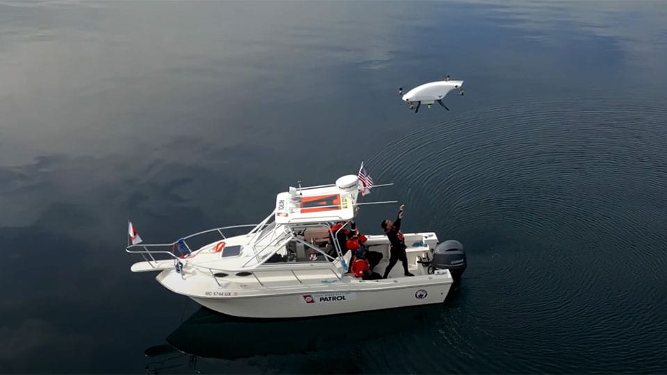 A drone flies above a patrol boat on the water during a mobility demonstration.