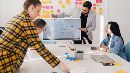 A small team collaborates around a large digital display in an office.