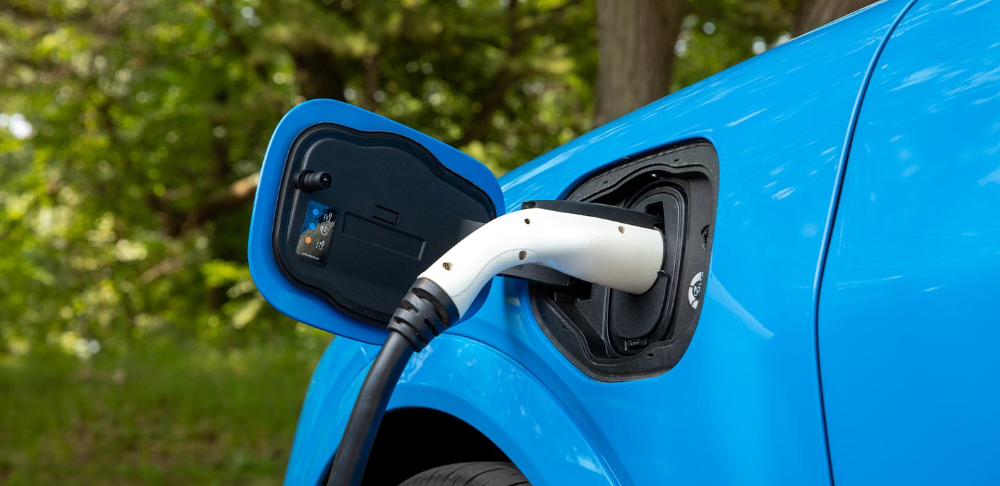 Close-up of a blue electric vehicle plugged into a charging cable.