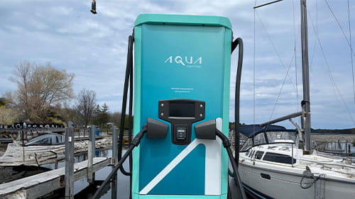 Aqua superPower rapid charger installed on a marina dock with boats in the background at Northport Marina.