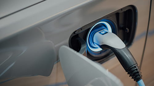 Close-up of an electric vehicle charging plug connected to a vehicle.