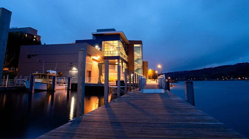 Waterfront research center at dusk with a wooden dock leading toward the building.