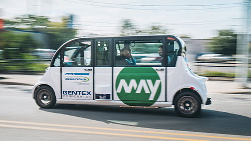 A May Mobility autonomous shuttle drives along a city street.