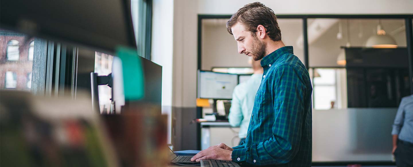Man using a laptop in a modern office workspace.