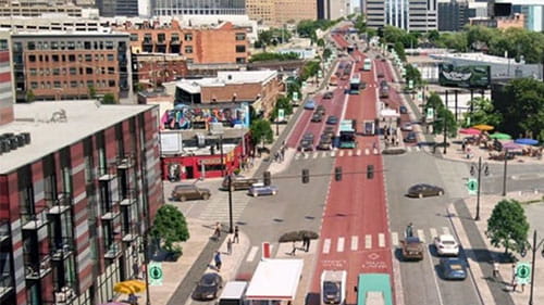 Aerial view of an urban roadway with red transit lanes, traffic, bike lanes, and crosswalks.