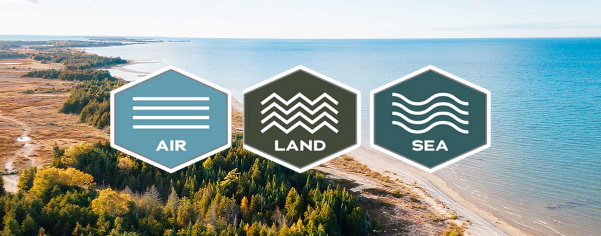 Aerial view of a Great Lakes shoreline with three overlay icons labeled Air, Land and Sea.