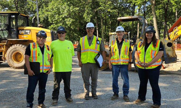 Five people in safety vests and helmets standing at a construction site in Oak Park during MIOSHA’s Take a Stand event.