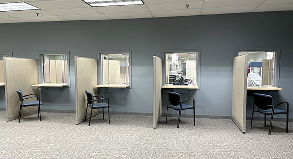 A local UIA office with new furniture and carpeting. The walls are a freshly painted greyish blue. There are four empty chairs in front of glass windows.