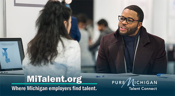 A person is talking to another person and a table is in between them. Text on the bottom of the graphic reads, "MiTalent.org: Where Michigan employers find talent." The right of the text shows the Pure Michigan Talent Connect logo.