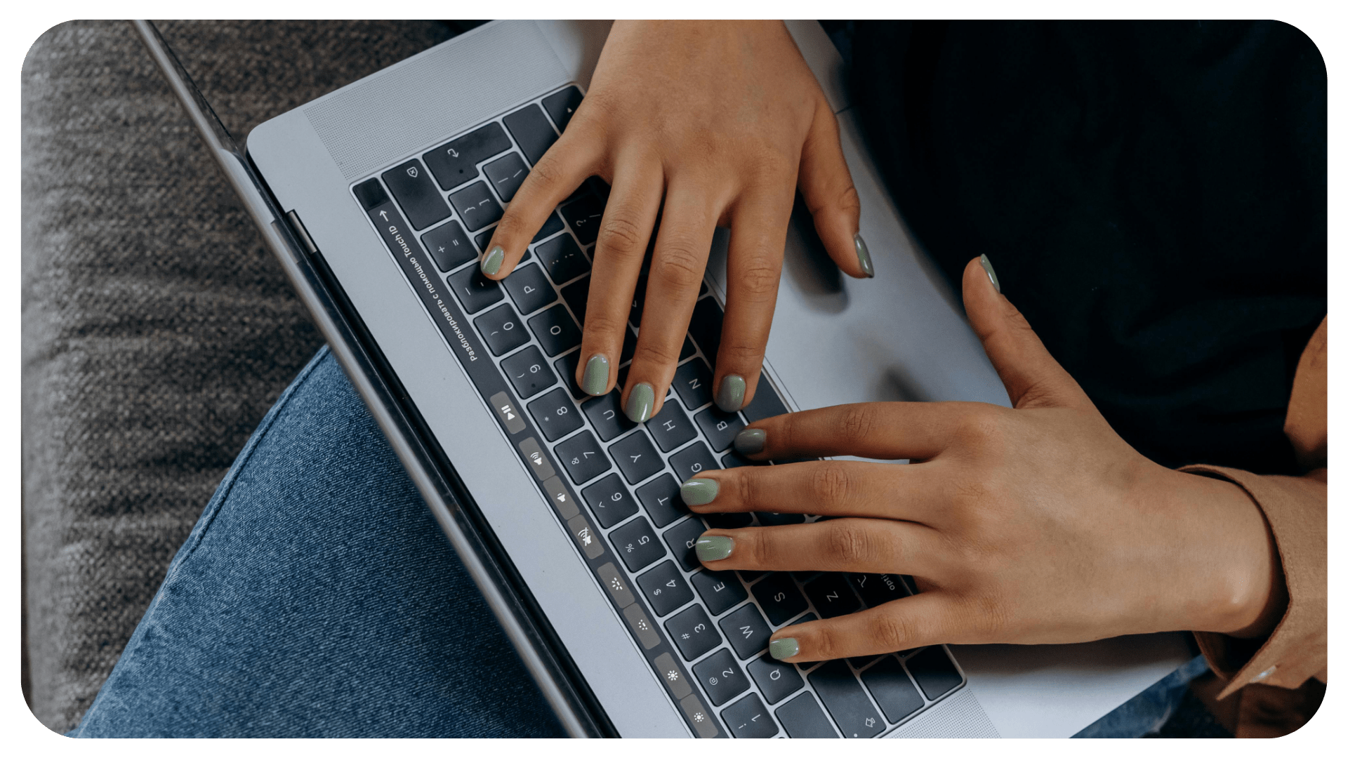 Two hands are typing on an Apple MacBook. The photo is an aerial view.