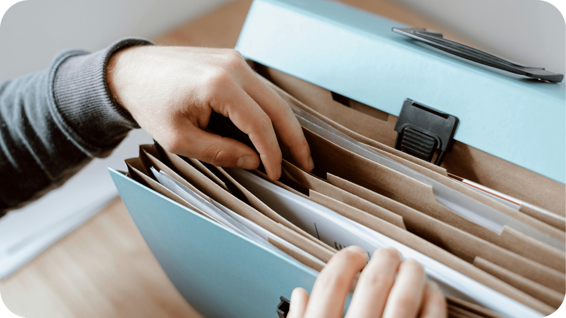 A pair of hands looking through a file folder.