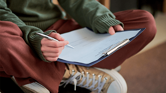 teen filling out a form on clipboard