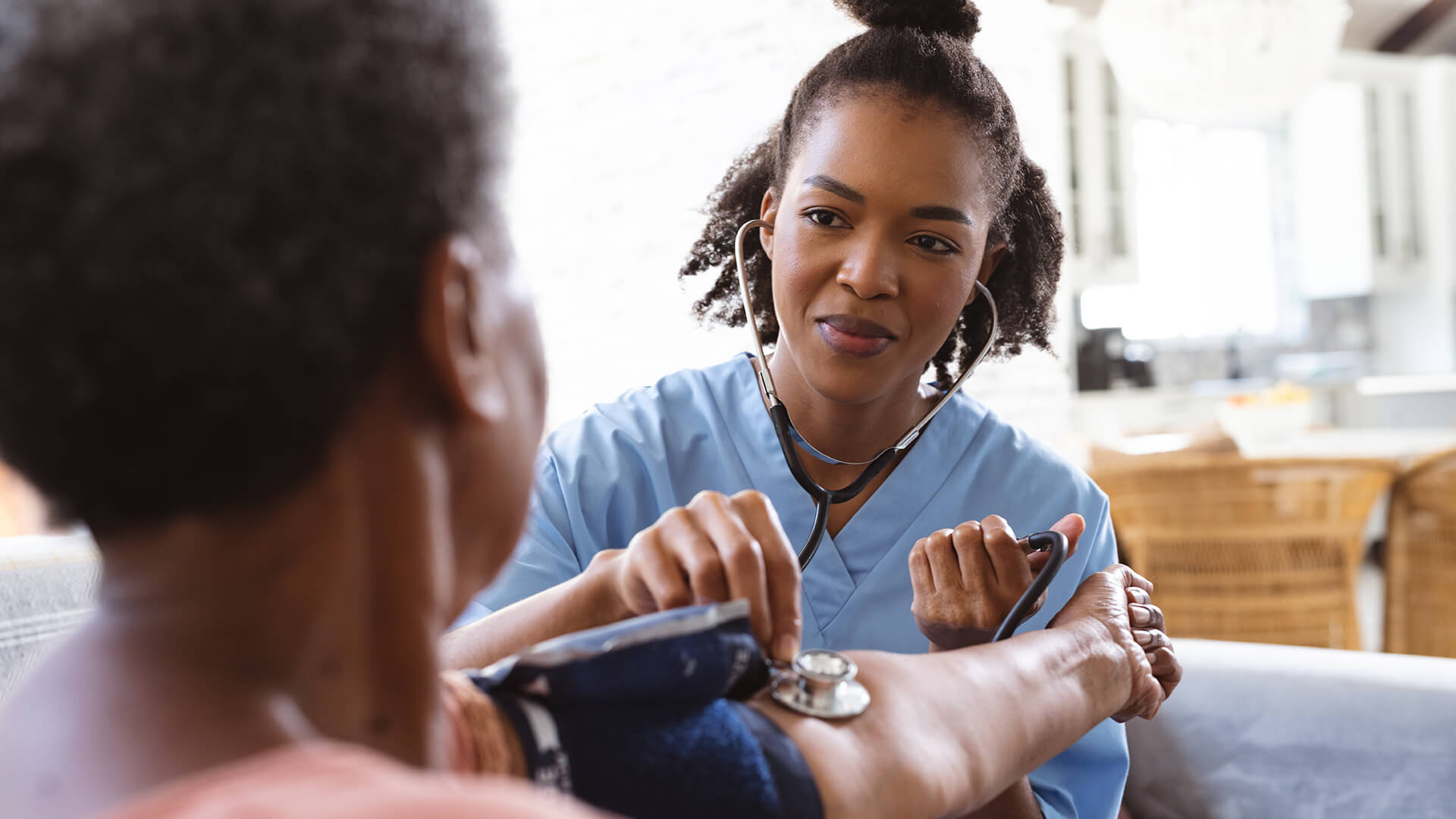 Healthcare worker measuring a patient’s blood pressure during an in-home care visit.