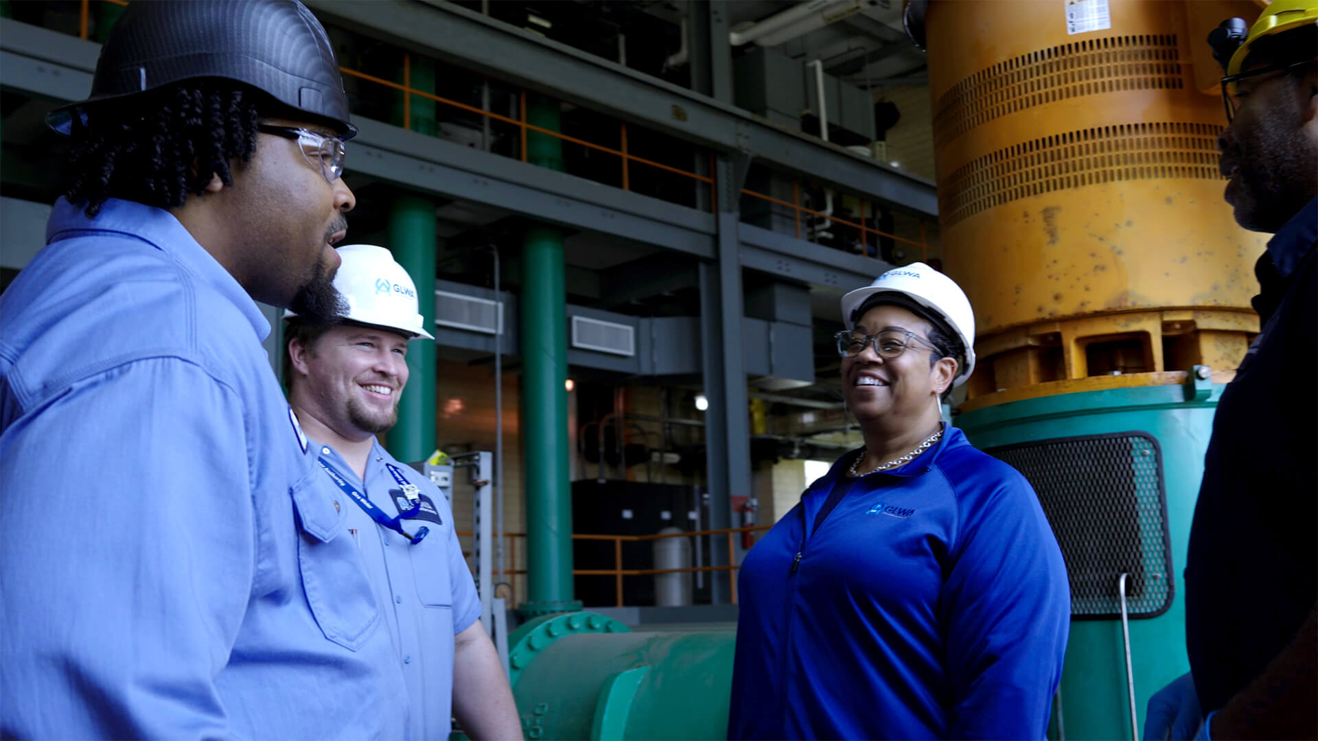 Group of people in hard hats talking inside an industrial facility.