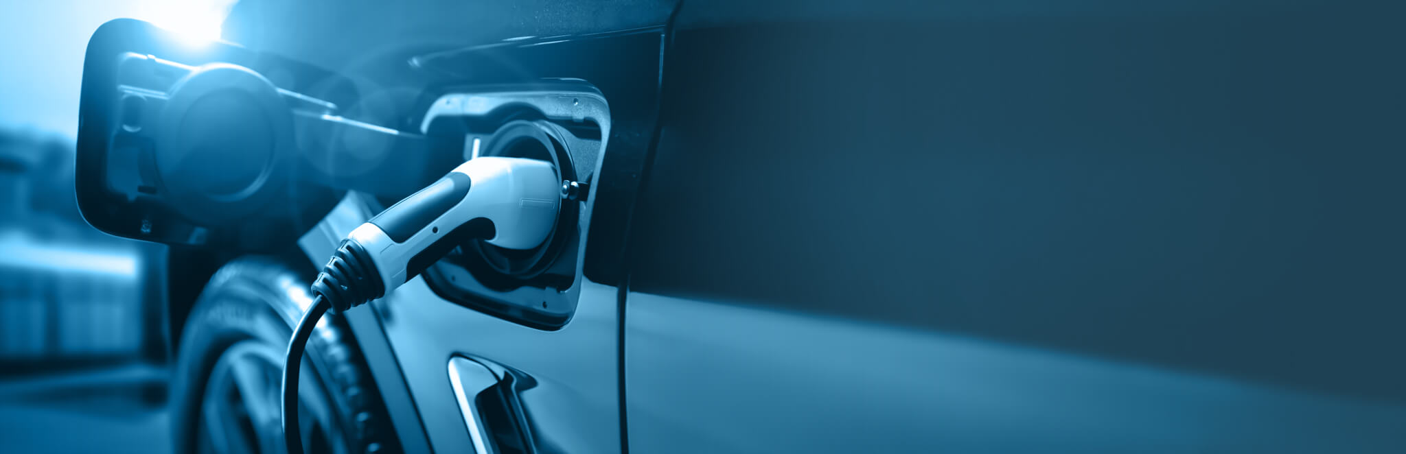 Closeup of an electric vehicle charging station J-plug inserted into the charging port of an electric car.