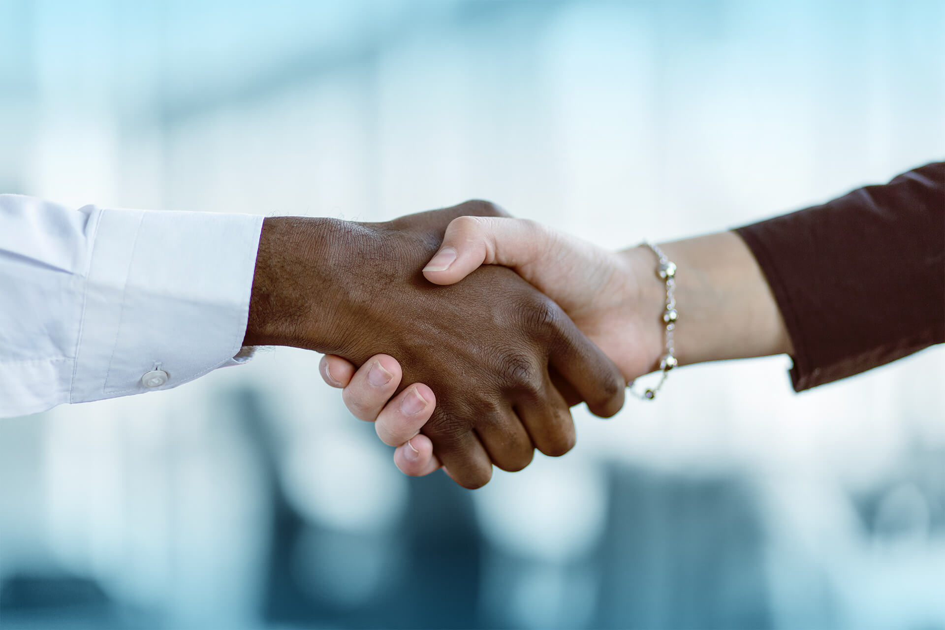Close-up of two people shaking hands, symbolizing partnership and agreement, with a blurred office background.