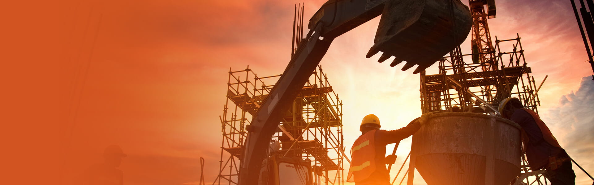A construction crew working on a job site with a backhoe bucket hanging overhead and scaffolding in the background.