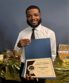 Trevon, a young, Black man in a shirt and tie holding open his MARC certificate.