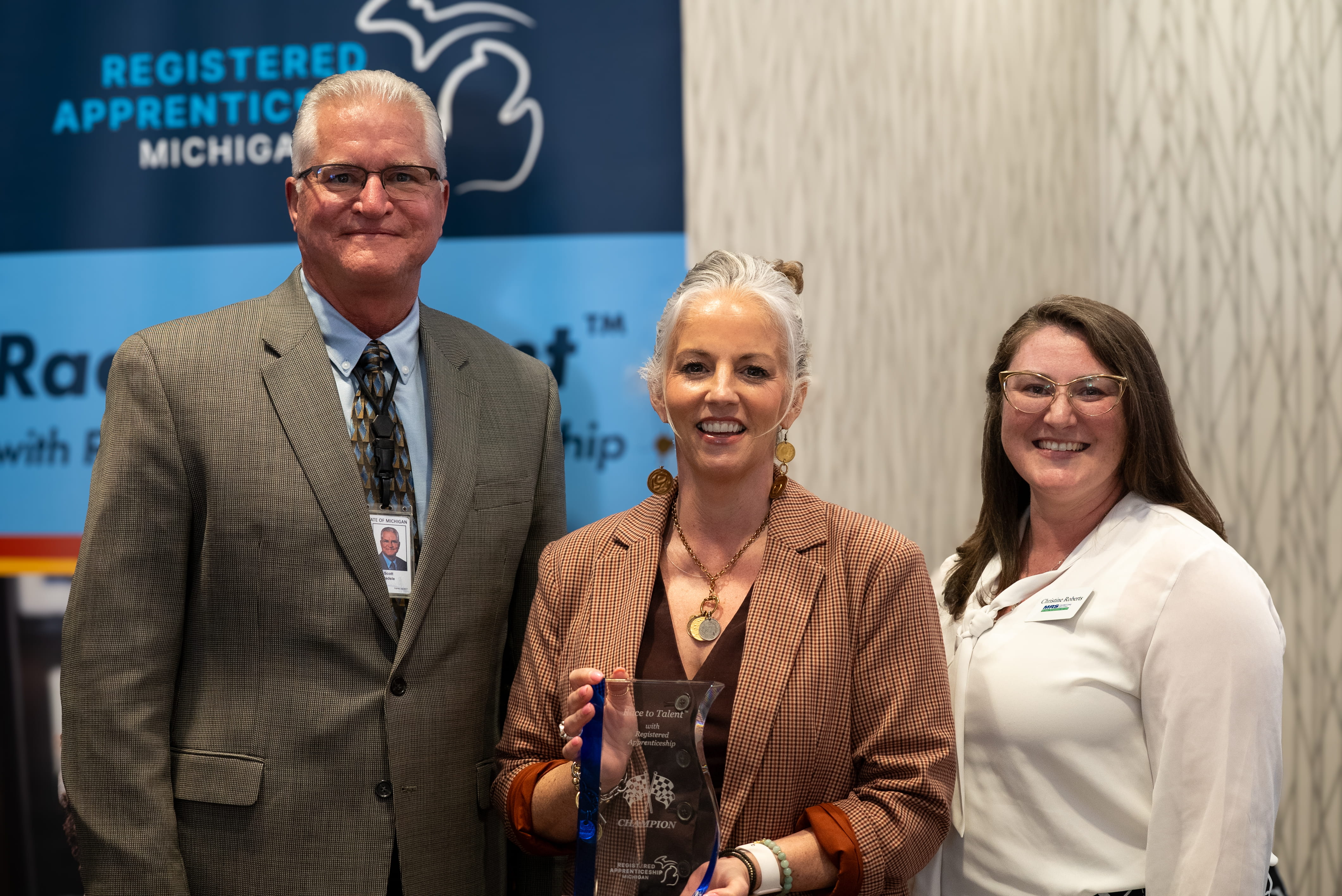 Alana Anderson (middle) holding a Race to Talent Champion award