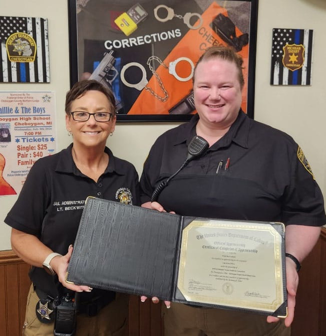 Nicole standing next to her mentor while holding her completion certificate