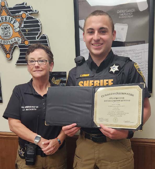 Jacob standing next to his mentor while holding his completion certificate