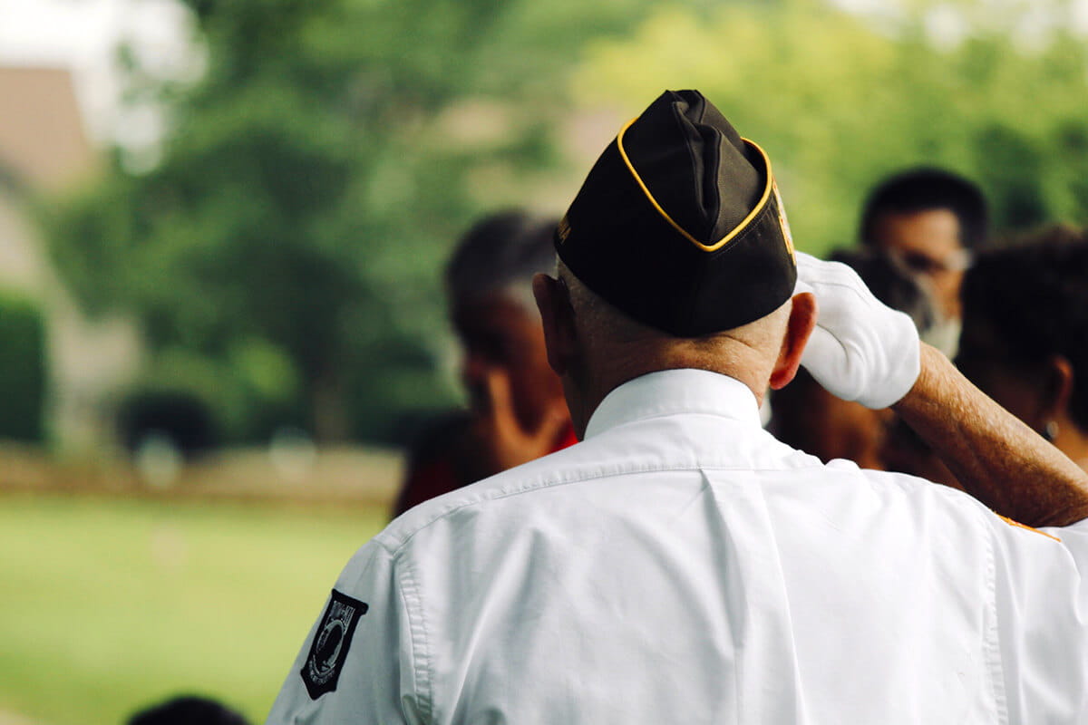 Elderly military veteran saluting while in dress uniform.