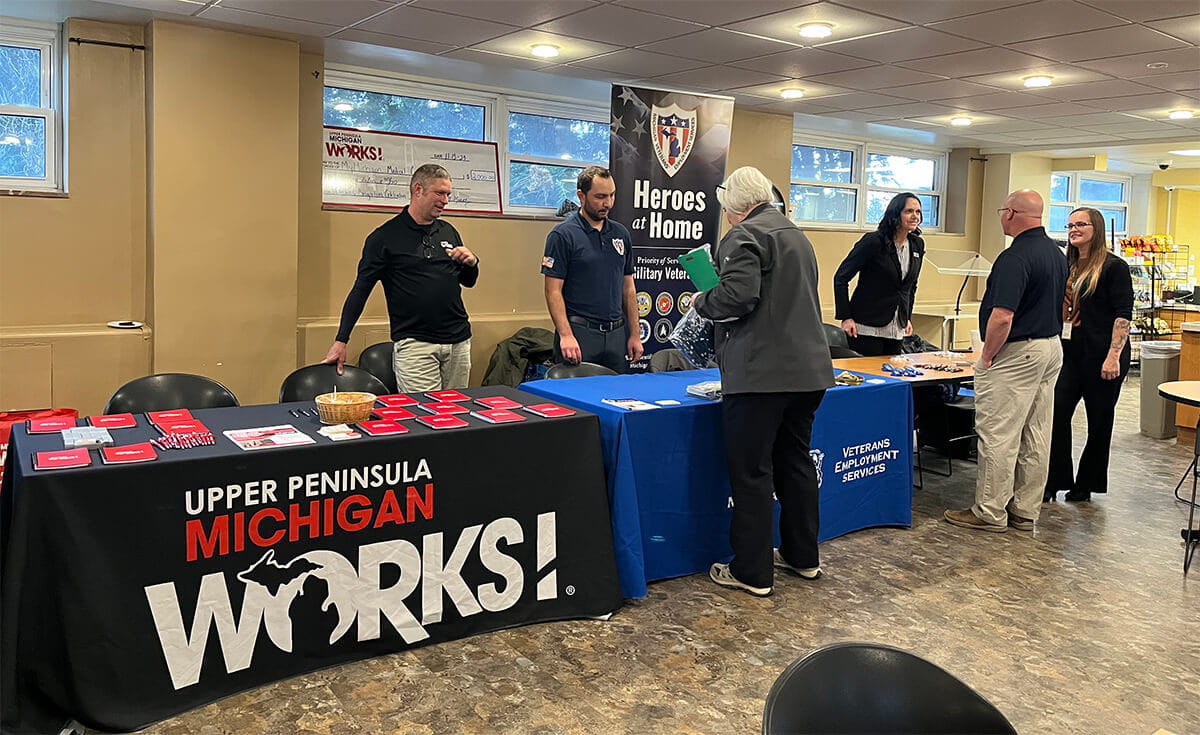 Event staff and attendees interacting at booths set up during a MI-PCS event held at Upper Peninsula Michigan Works!