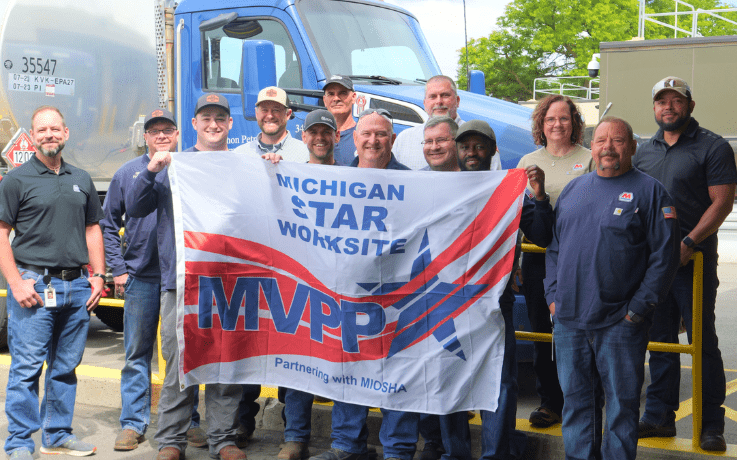 Marathon Romulus Terminal employees hold a Michigan Voluntary Protection Program STAR Worksite flag