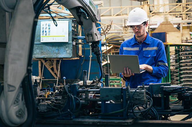 Man working on part of a car with a robot