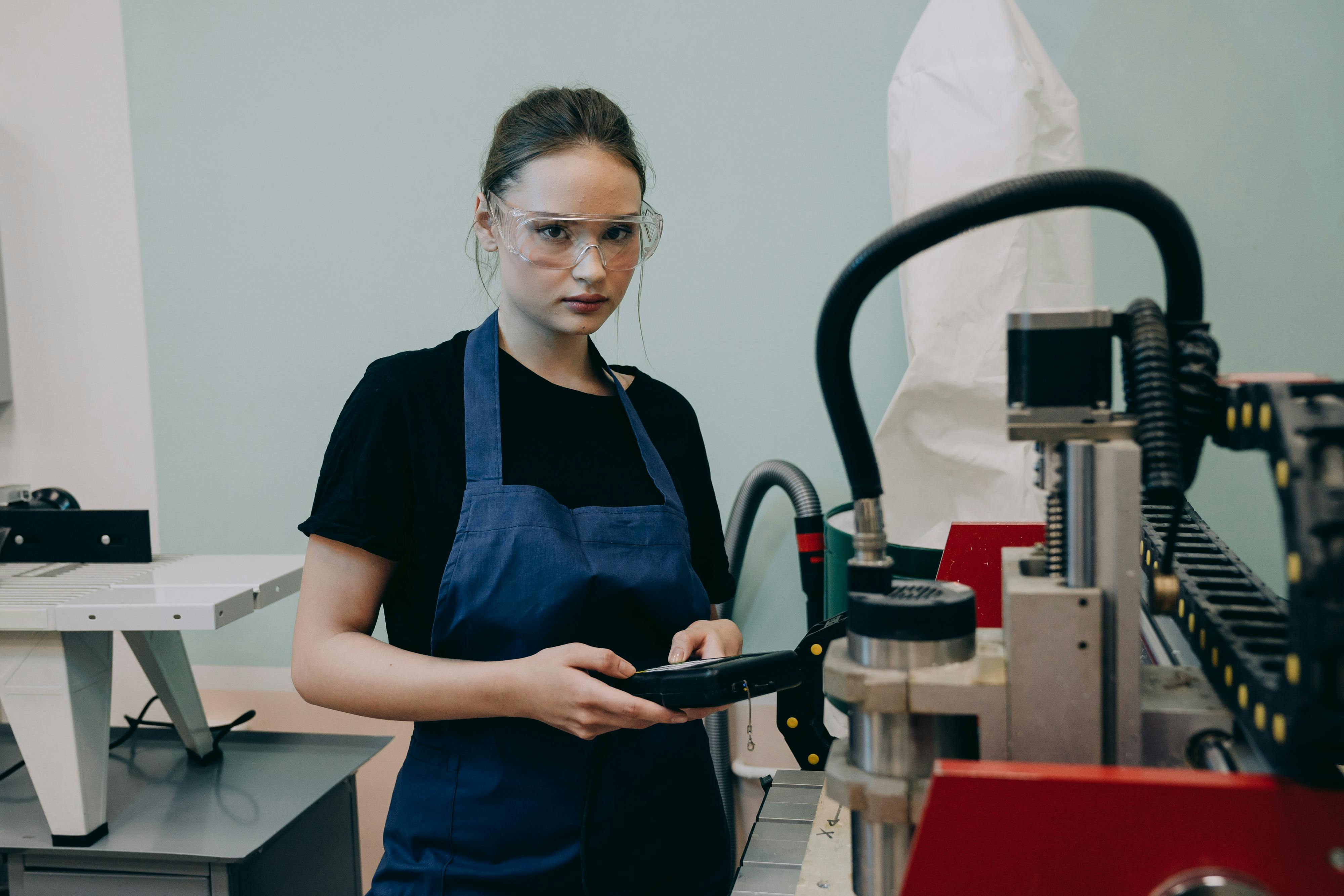 A young woman operating a CNC machine.