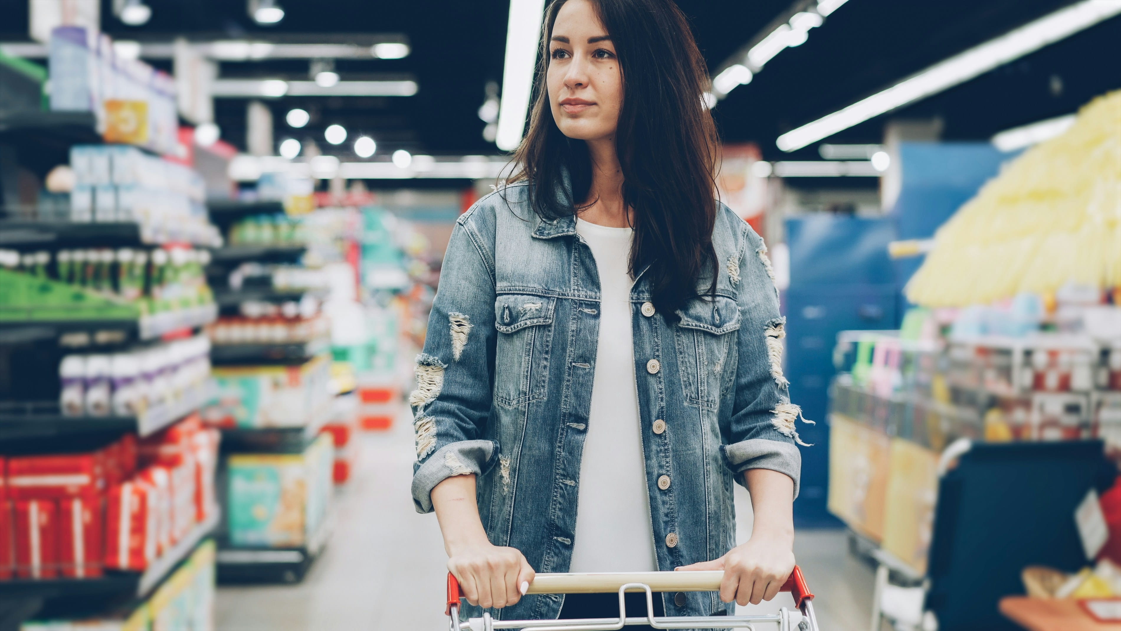 woman pushing shopping cart and walking through grocery store