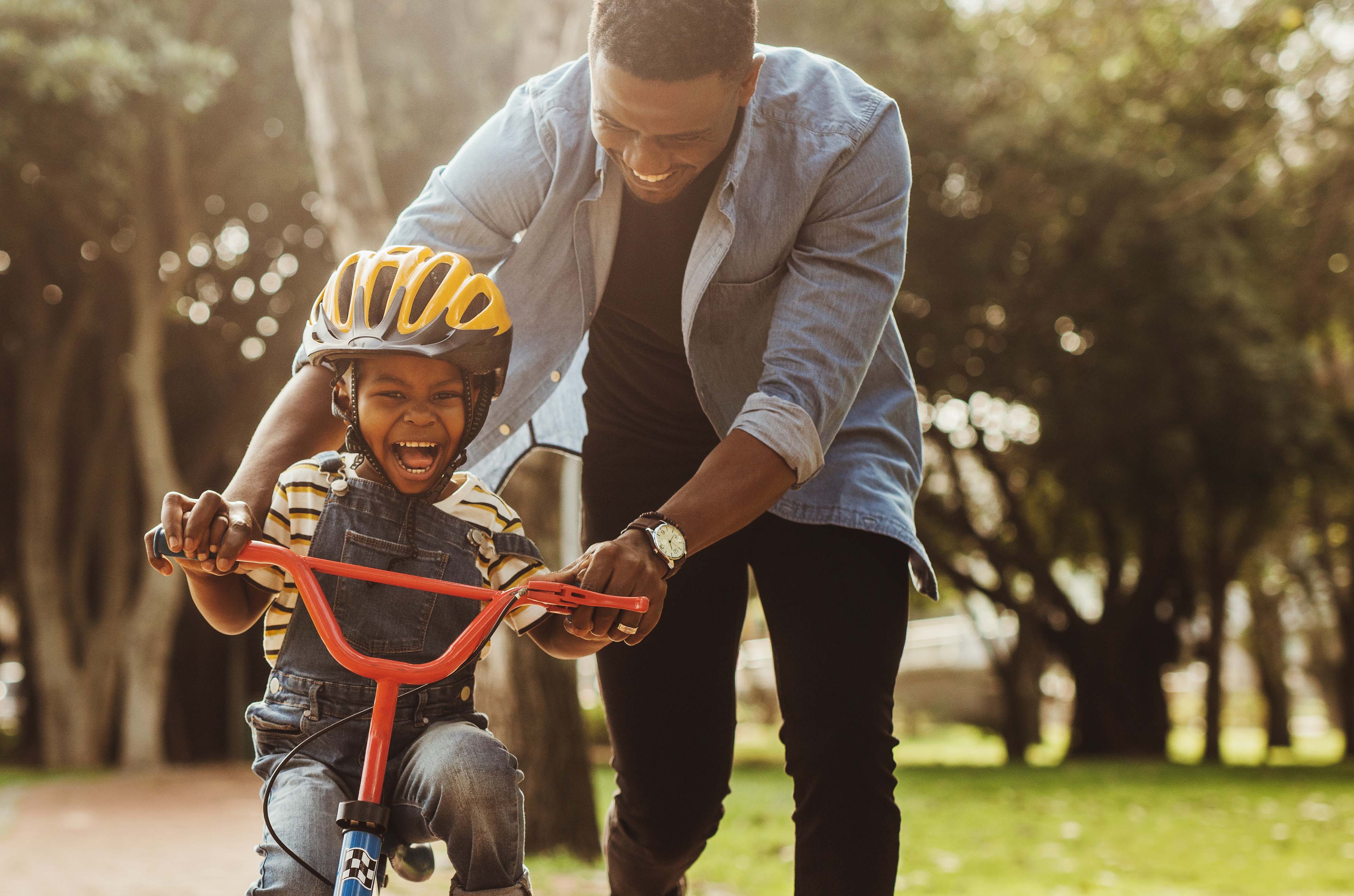 father helping young boy to ride a bike