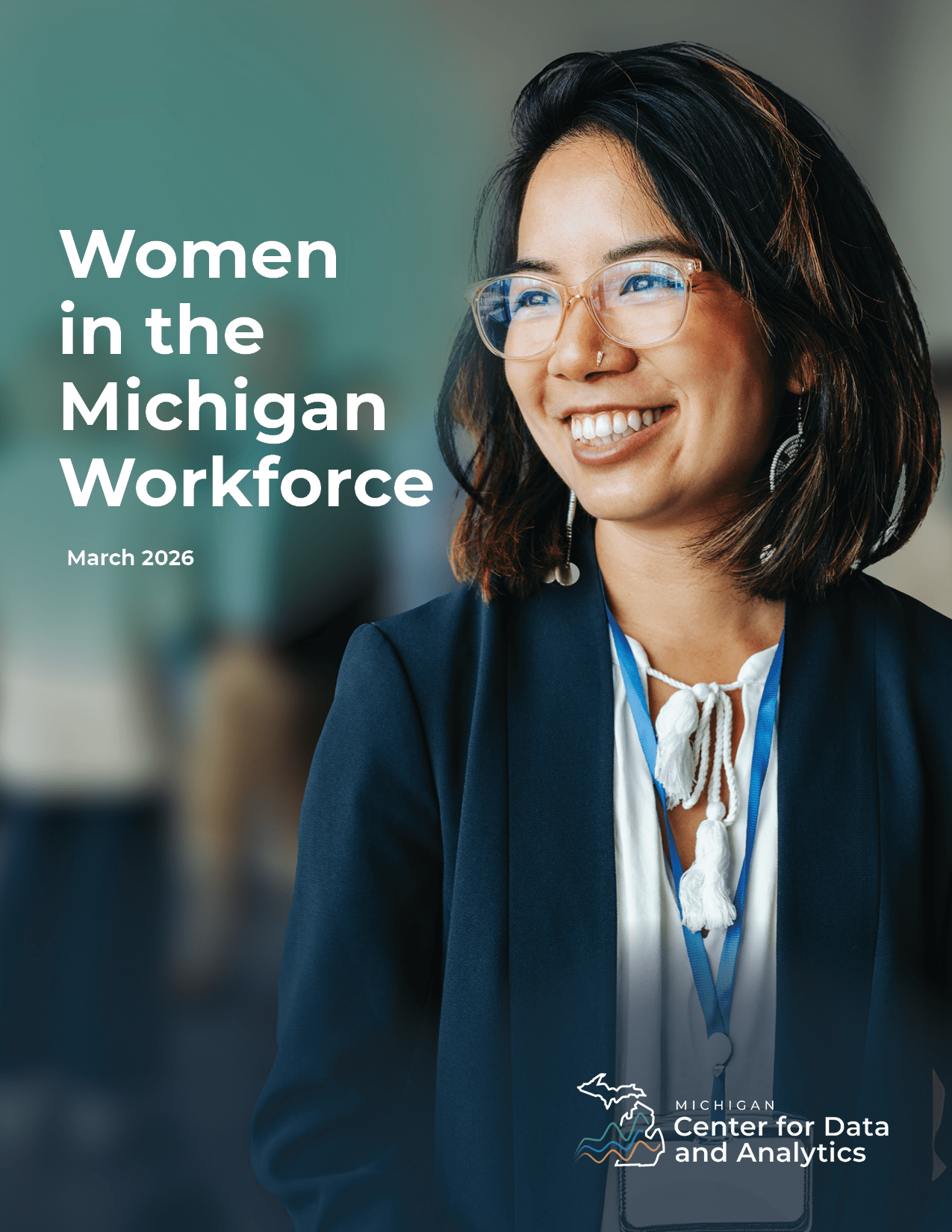 Woman in business professional clothing and a lanyard smiling and looking to the left of the camera