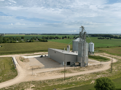 The Reese building facilities and parking lot, their farm fields visible in the background.