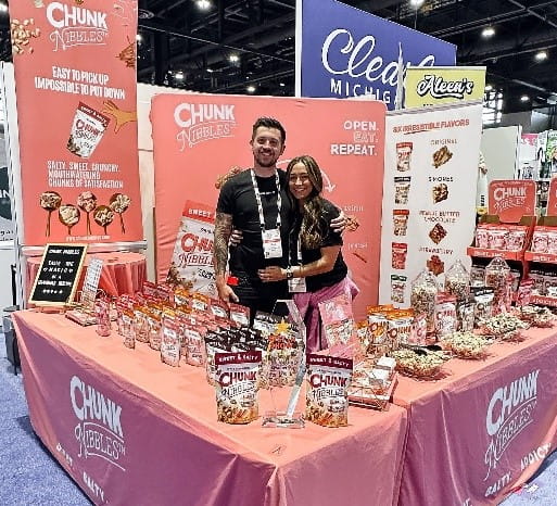 Brad and Katie Cocklin with the Chunk Nibbles booth at Sweets & Snacks Expo 2023.